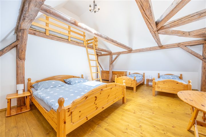 Podkrovní ložnice s postelemi a žebříkem do galerie